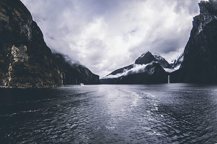 Body of Water Surround by Mountains Under Cloudy Sky