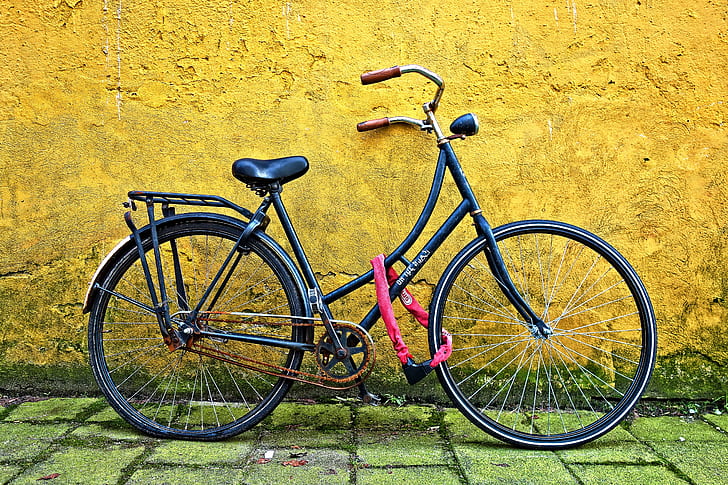 black bicycle beside yellow wall