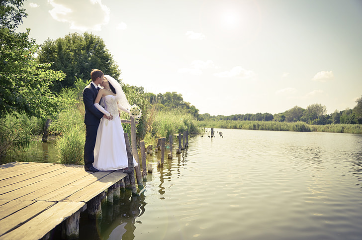 bride and groom standing on dock during daytime