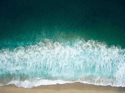 aerial photography of green seashore with crushing waves during daytime