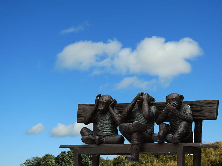 three wise monkeys sitting on bench statues