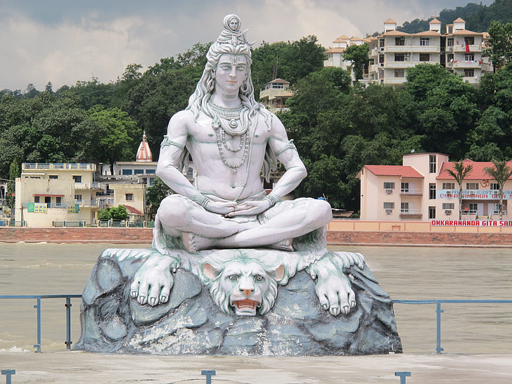 statue of Hindu Deity sitting on white tiger near river