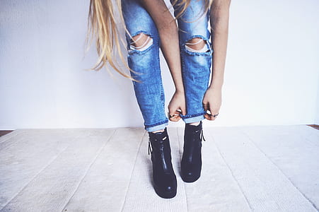 woman wearing blue distressed jeans and pair of black leather boots