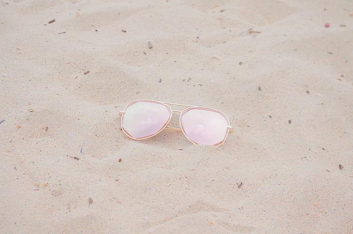 aviator sunglasses with gold frames on sand