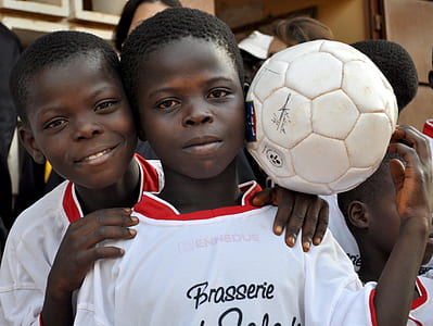 two boy wearing white t-shirt holding soccer ball