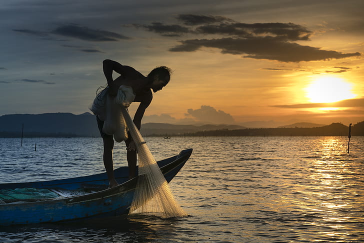 person riding row boat while holding fishing net
