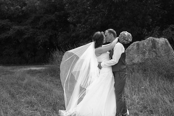 grayscale photo of newly wedding couple kissing