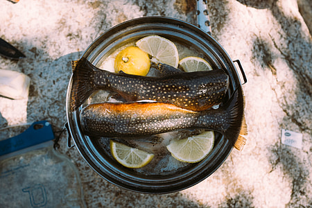 two black fish's tails with lemon in cooking pot