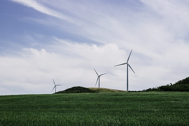 three gray wind turbines on green grass field