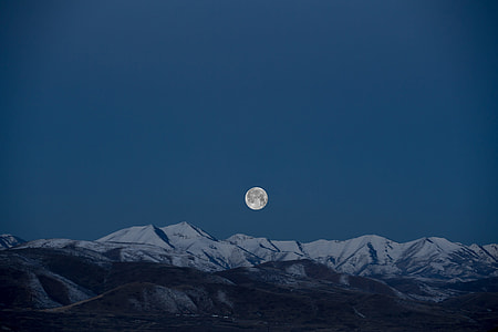 photo of full moon above snow-covered hills
