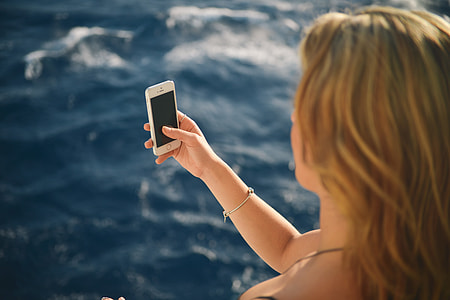woman taking selfie in front of body of water during daytime