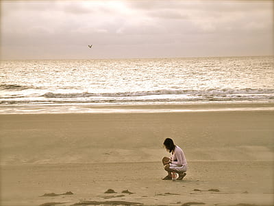 Woman in Pink Cardigan Sitting on Seashore