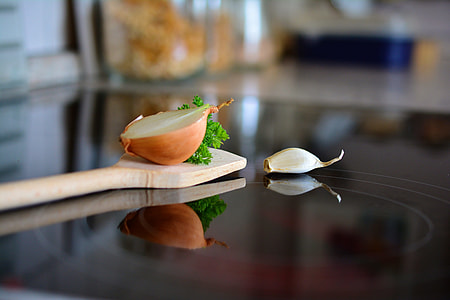 tilt shift photo of brown wooden lade with sliced onion beside white garlic