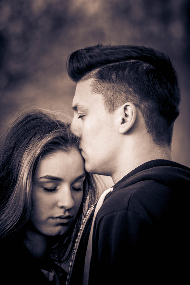 sepia photo of man kissing woman's head