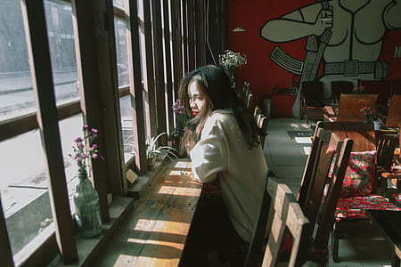 Woman Sitting on Chair Leaning on Table and on Facing Window