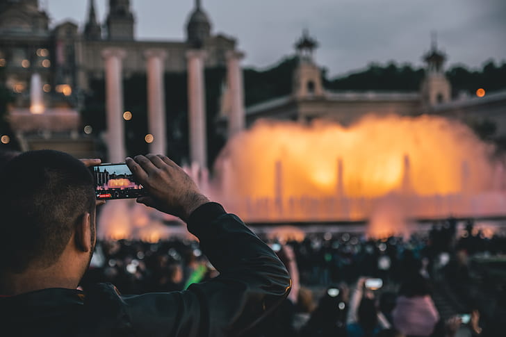 man in black leather jacket taking photo of outdoor fountain