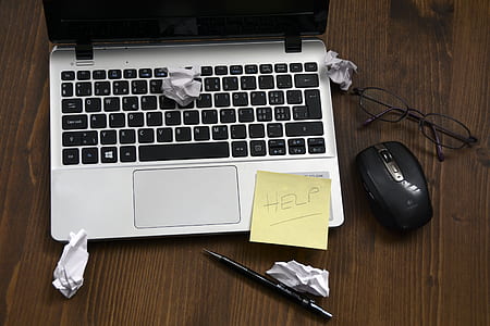 yellow sticky note on gray laptop computer beside black wireless mouse and black framed eyeglasses