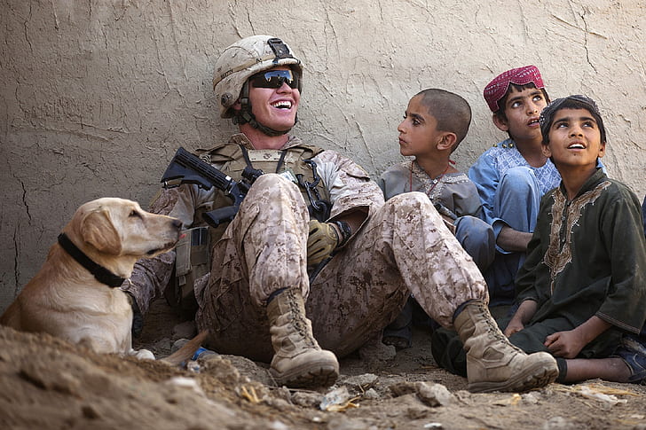 soldier sitting beside three children and adult yellow Labrador retriever