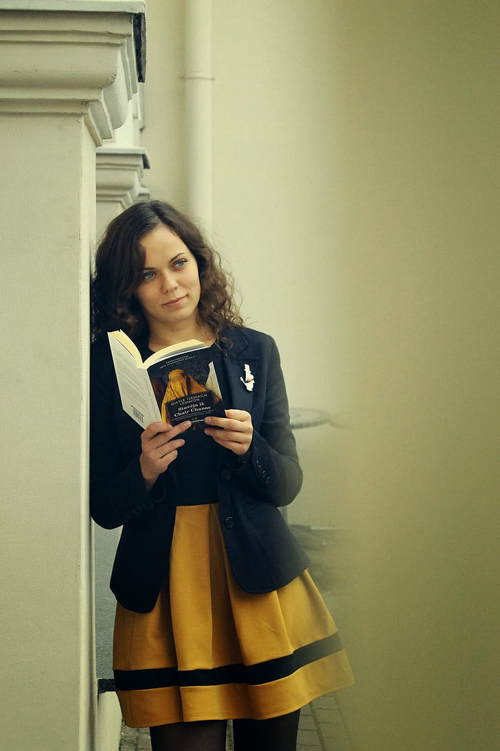 woman wearing black and yellow dress and holding a book