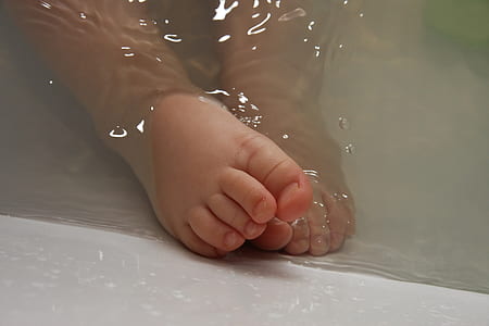 closeup photo of baby's foot on body of water