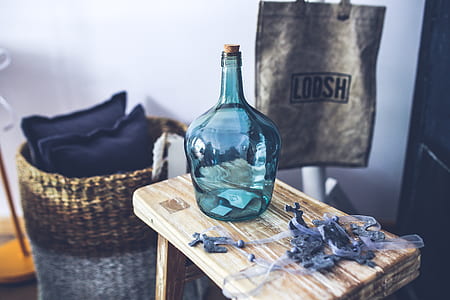 teal glass bottle on brown wooden saddle stool