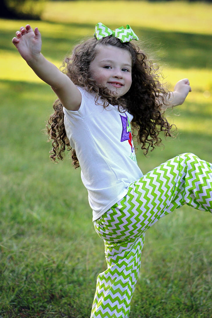 girl in white shirt and green chevron pants doing dance moves during daytime