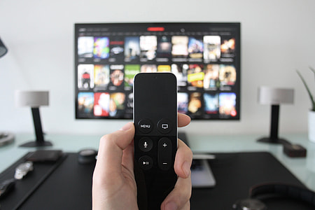Man using Apple Television with remote control for movies