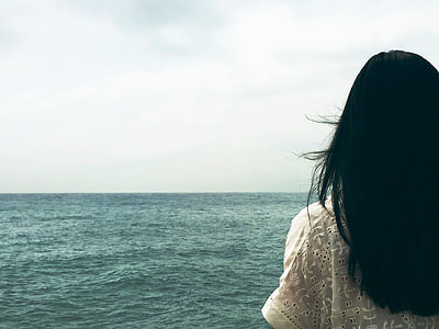 black haired woman near body of water during day time