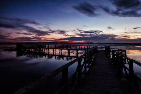 sea dock over calm body of water at sunset