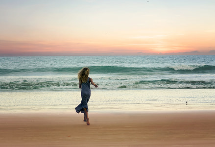 woman wearing blue dress near seashore at sunset