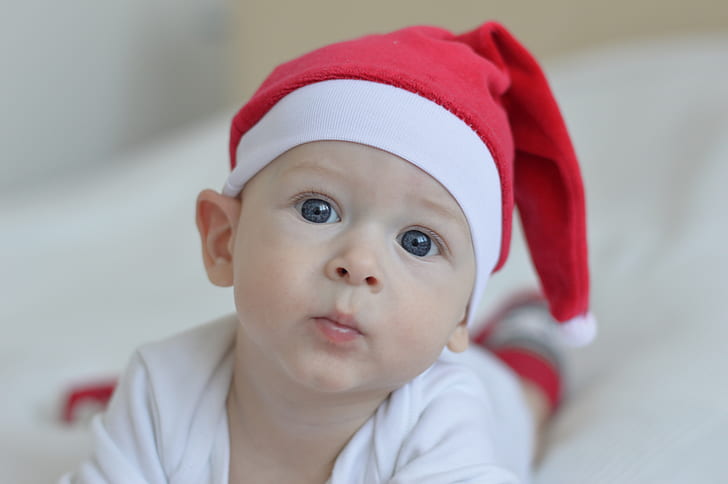 boy wearing white shirt and red Santa hat