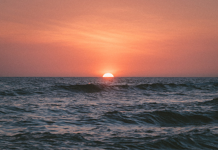 orange sky over waving ocean during sunset