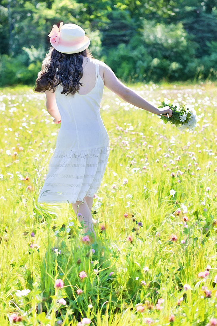 woman in white spaghetti strap dress on green-and-pink flower field during daytime