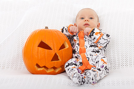 baby boy wearing white and orange footie pajama beside jack o lantern