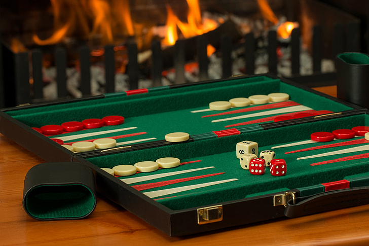 green, red, and white backgammon board on brown wooden tabletop
