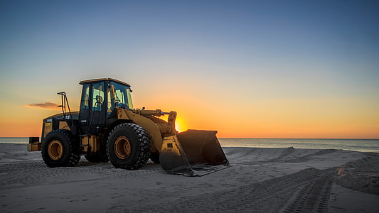 yellow and black bulldozer parked on grey sand