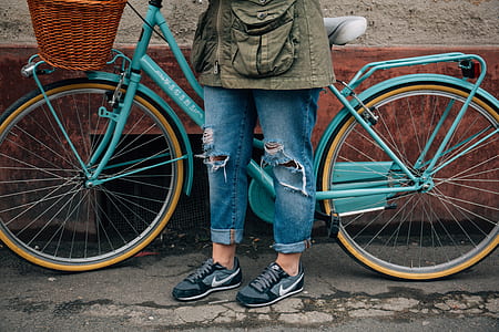 person wearing blue denim jeans standing near blue bicycle