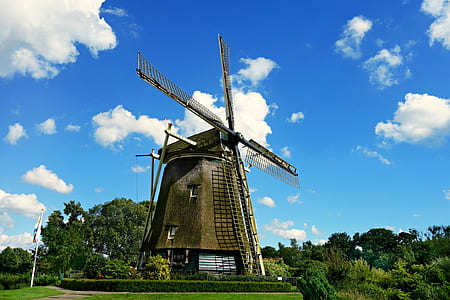Brown and Black Windmill Under Cumulus Clouds Surrounded by Green Leaf Trees