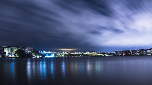 time lapse photograph of a city full of building near bodies of water in nighttime
