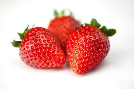 Close-up macro shot of fresh strawberries on a white background, image captured with a Canon 5D