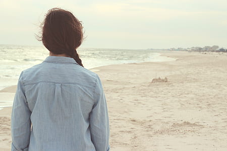woman wearing blue collared shirt standing near seashore