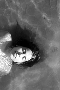 grayscale photo of woman lying on water