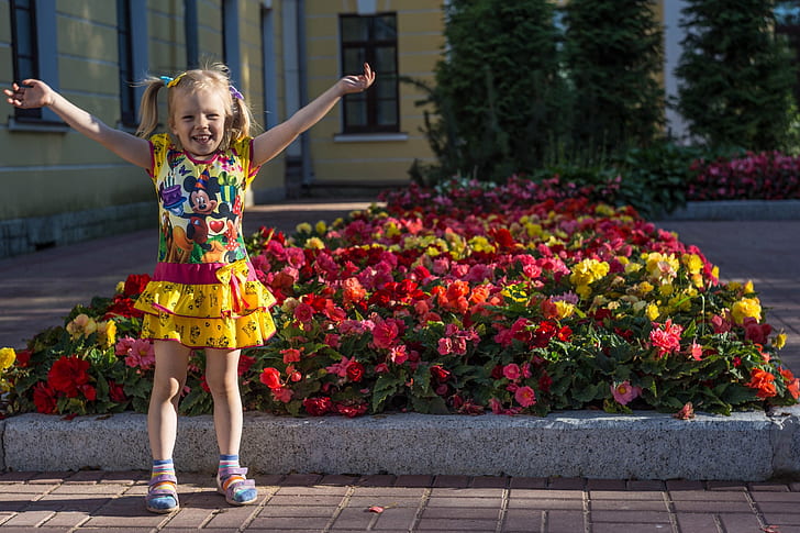 girl wearing Minnie Mouse-printed dress behind flower lot