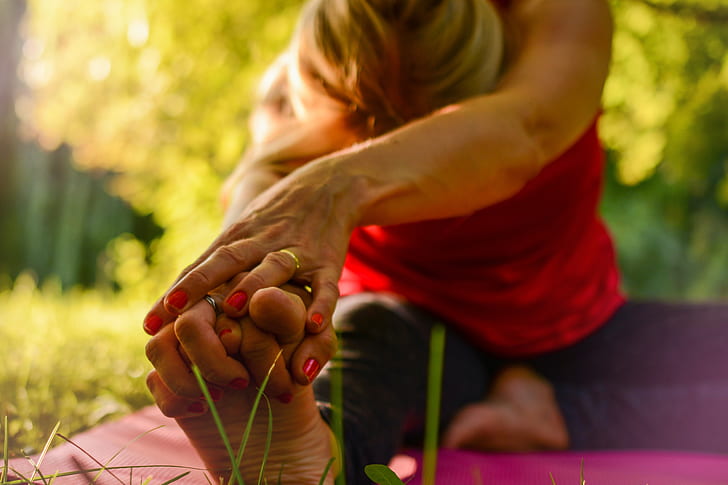 woman wearing red shirt with gold wedding ring working yoga