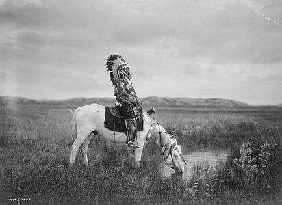 grayscale photography of Native American ride-on horse in grass field