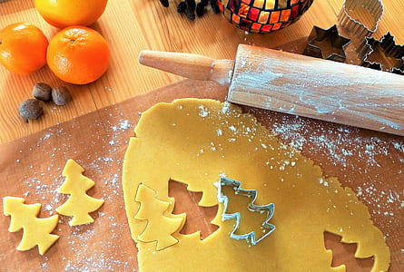 dough cut with Christmas tree form beside rolling pin