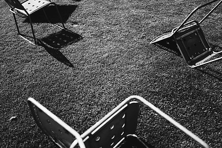 gray scale of three steel chair on ground