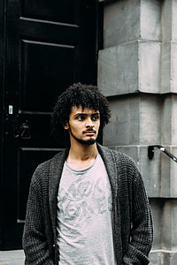 man in grey crewneck T-shirt and grey cardigan standing on black door