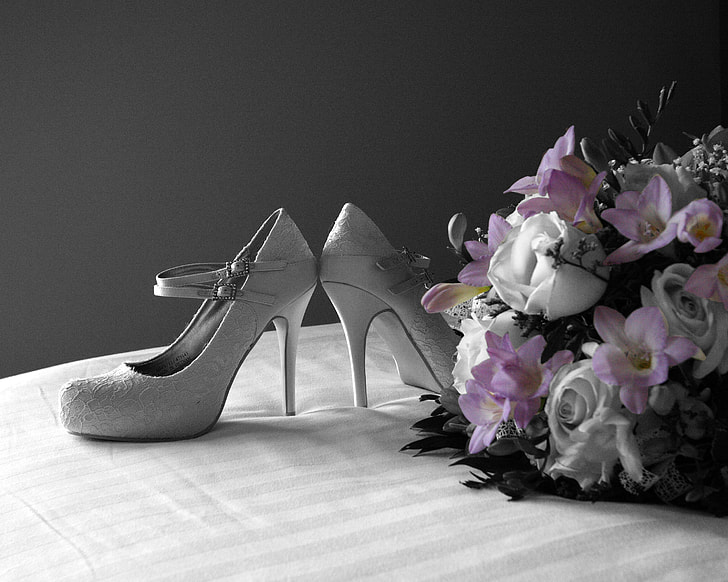 pair of women's gray stilettos beside pink and white flower bouquet