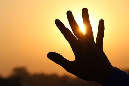 Man’s hand extended at sunset